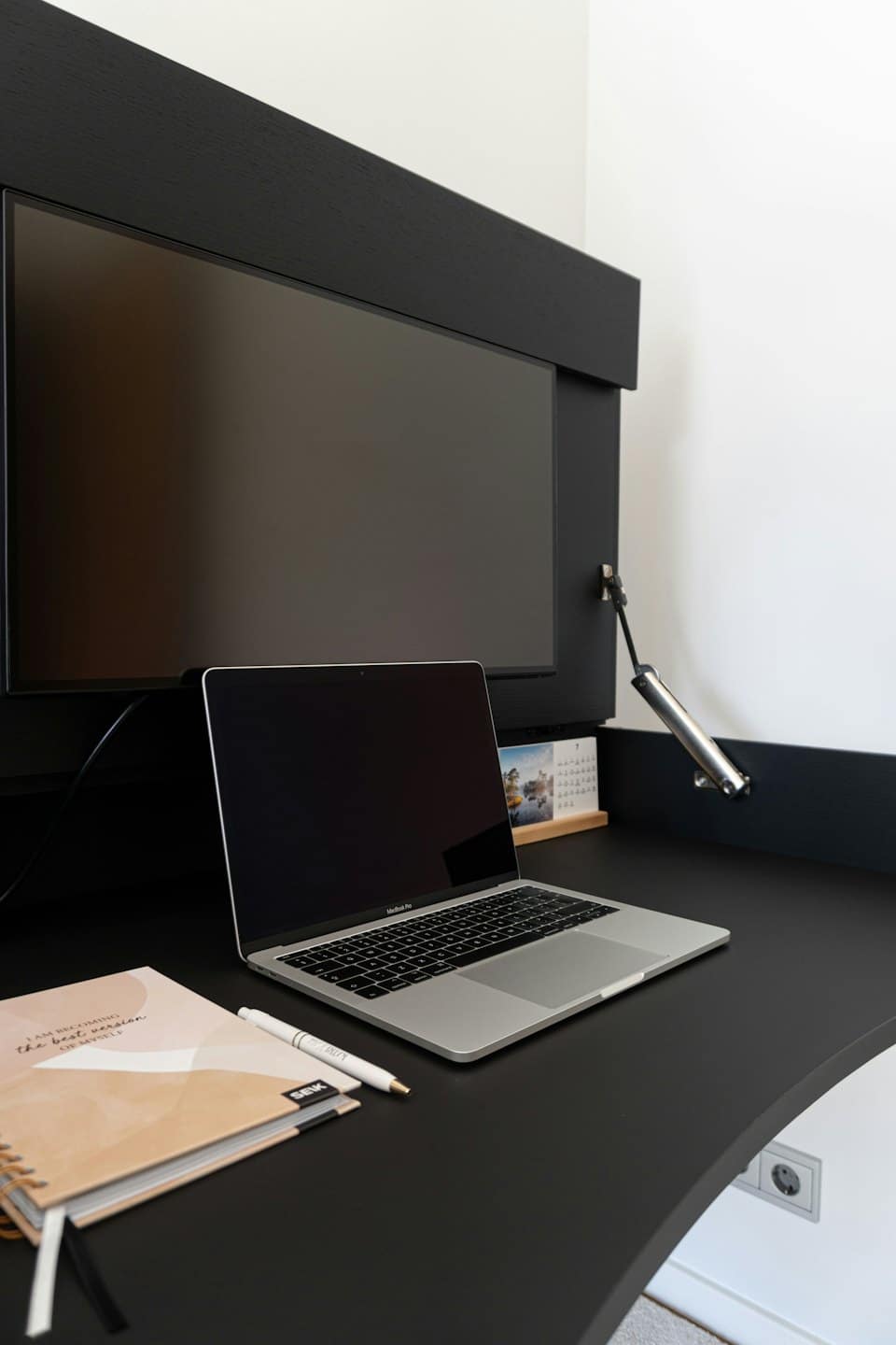 Computer portatile e taccuino su una scrivania moderna per ufficio domestico.