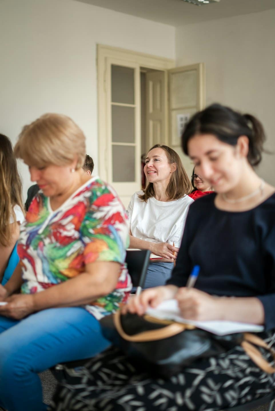 Partecipanti coinvolti in un workshop, in ascolto attento di un relatore.